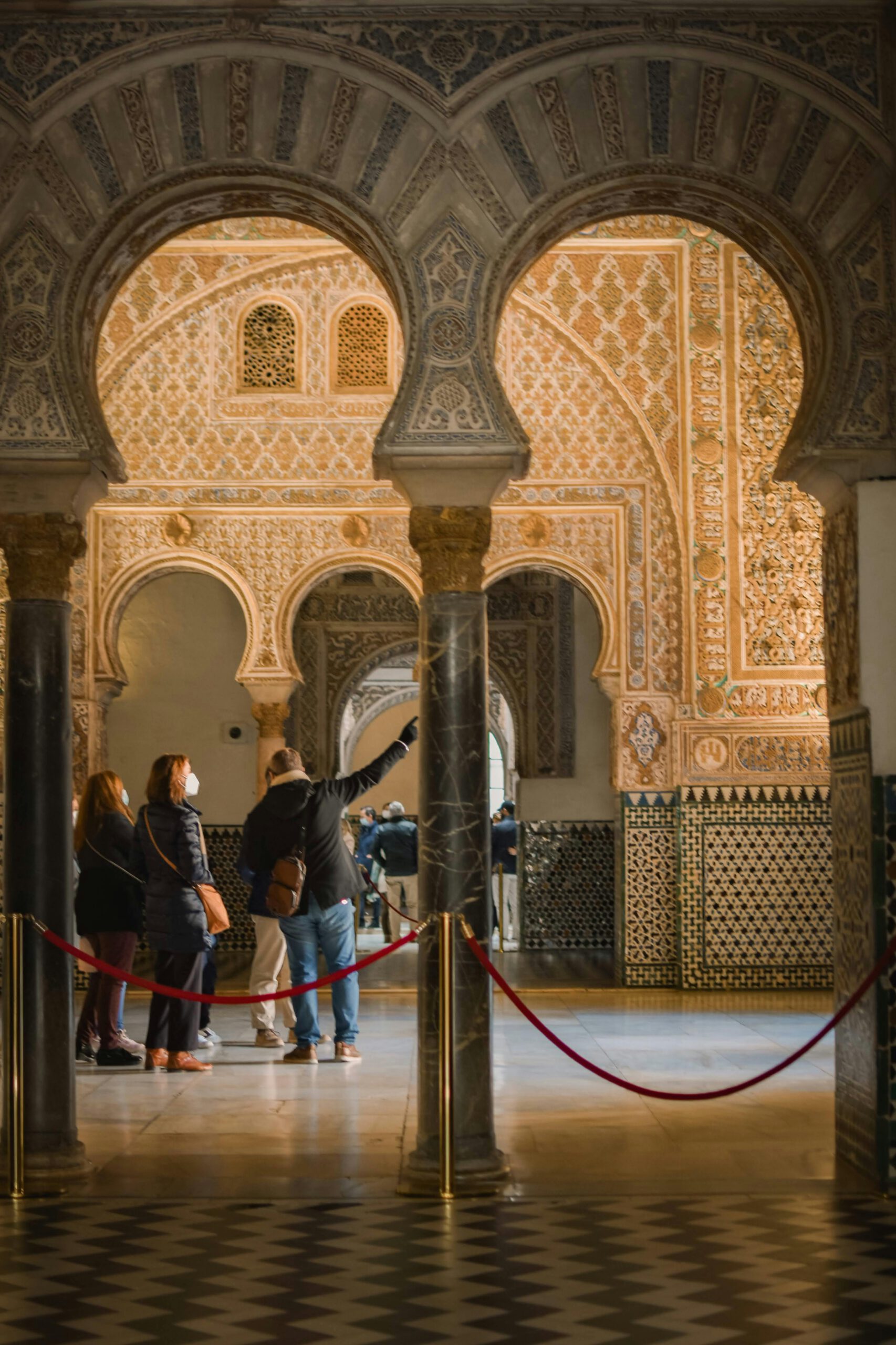 Tourists admire the intricate Moorish arches and designs inside a historic building.